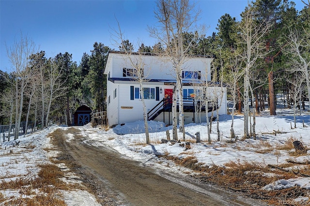 view of front of home featuring driveway, stairs, and an outbuilding