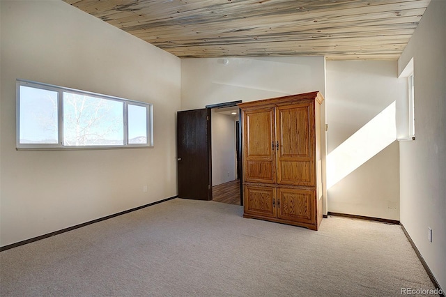 unfurnished bedroom with lofted ceiling, wooden ceiling, baseboards, and light colored carpet