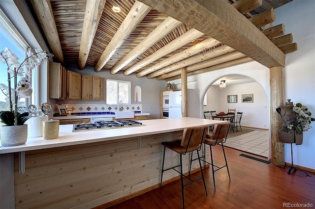 kitchen with arched walkways, wood ceiling, white refrigerator, a peninsula, and stainless steel gas cooktop