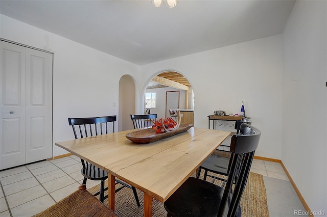 dining space with baseboards, arched walkways, and light tile patterned flooring