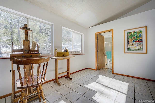 interior space featuring lofted ceiling, a textured ceiling, baseboards, and light tile patterned floors