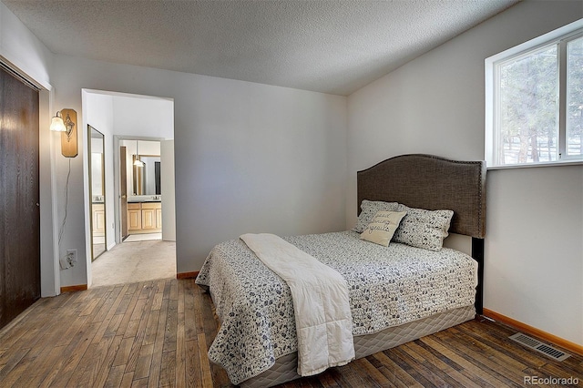 bedroom with baseboards, visible vents, a textured ceiling, and hardwood / wood-style floors