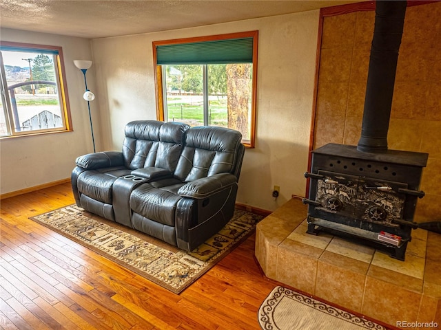 living room featuring hardwood / wood-style floors, a wood stove, a textured ceiling, and a wealth of natural light