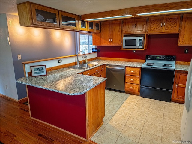 kitchen featuring kitchen peninsula, sink, dark stone counters, and appliances with stainless steel finishes