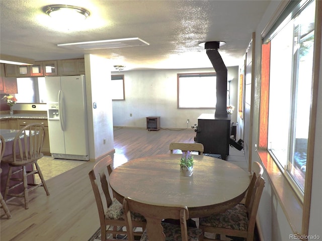 dining space with light hardwood / wood-style floors, a wood stove, and a textured ceiling