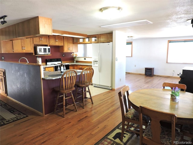 kitchen featuring a textured ceiling, white appliances, light hardwood / wood-style flooring, and sink