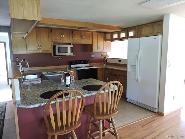 kitchen featuring sink, stone countertops, white appliances, and light hardwood / wood-style flooring