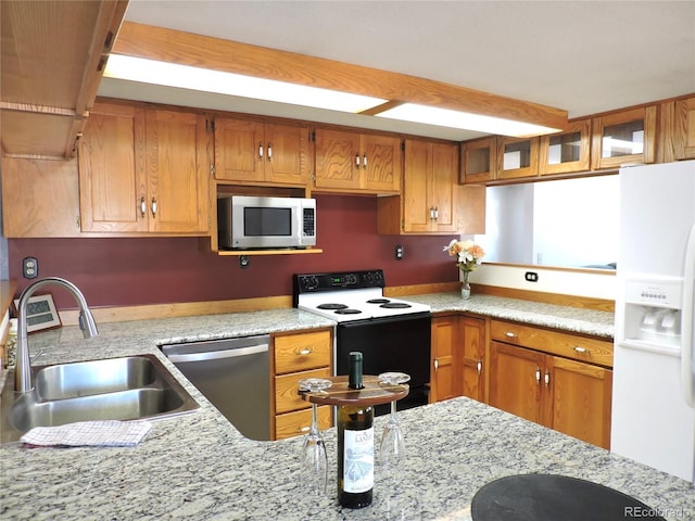 kitchen featuring light stone countertops, sink, and white appliances