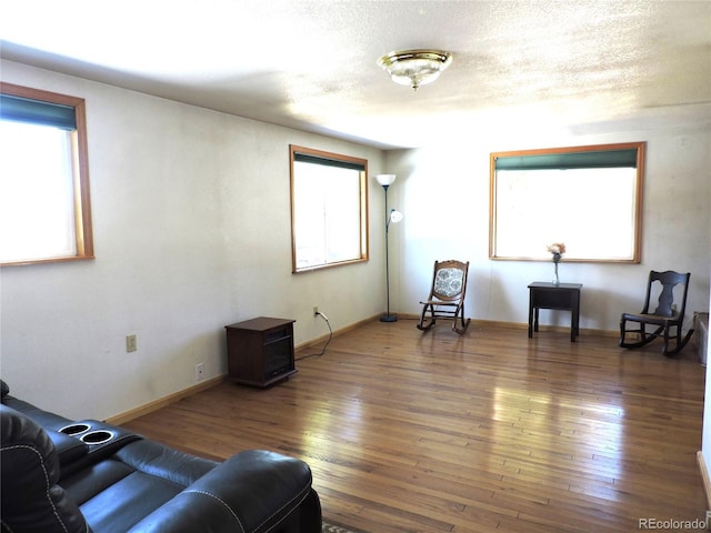 living area with dark wood-type flooring and a textured ceiling