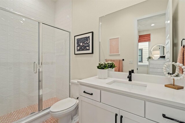 bathroom featuring vanity, a shower with door, and toilet