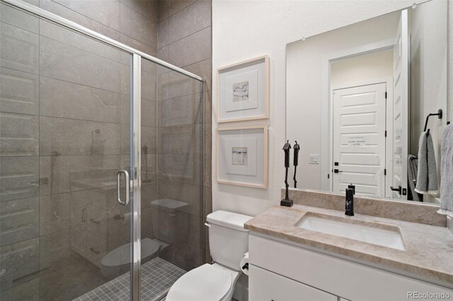 bathroom with a shower with door, vanity, and toilet