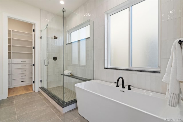 bathroom with tile walls, tile patterned flooring, and shower with separate bathtub