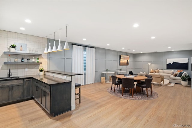 kitchen featuring light wood-type flooring, pendant lighting, a kitchen breakfast bar, and kitchen peninsula