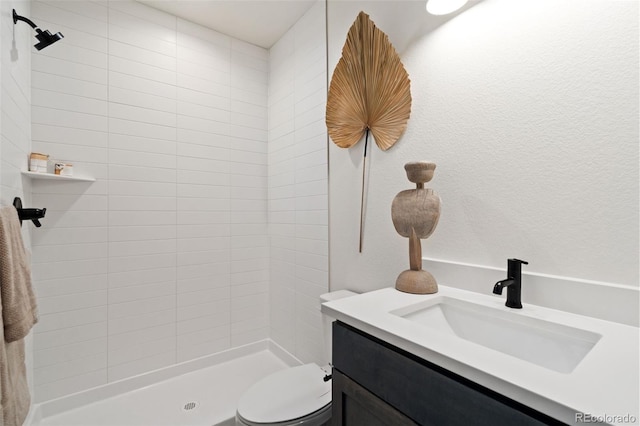 bathroom featuring vanity, tiled shower, and toilet