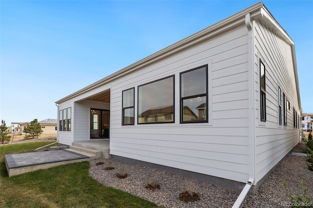 view of property exterior with a patio area and a lawn