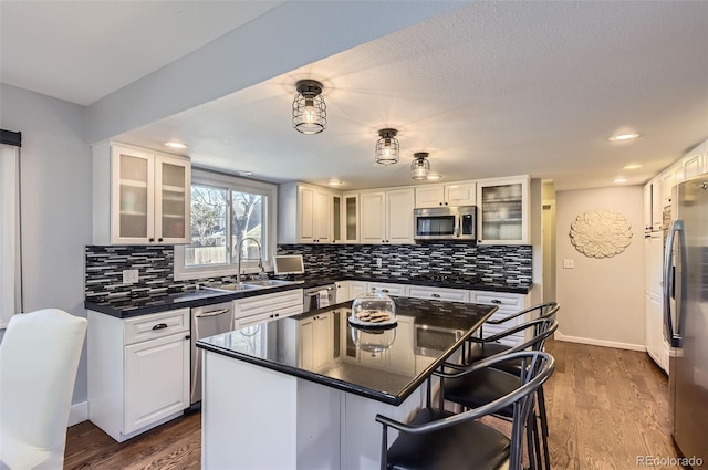 kitchen featuring white cabinets, appliances with stainless steel finishes, sink, and a center island