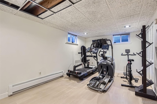 workout room with hardwood / wood-style floors, a drop ceiling, and a baseboard radiator