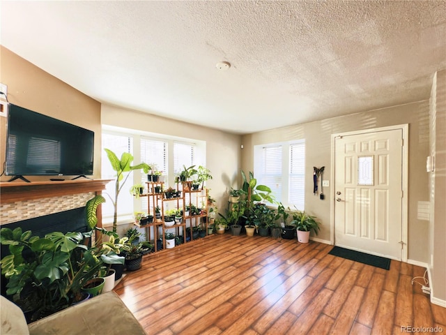 1120 S Waco St Unit A, Aurora, CO 80017 - entrance foyer featuring hardwood / wood-style floors, a textured ceiling, a fireplace, and baseboards
