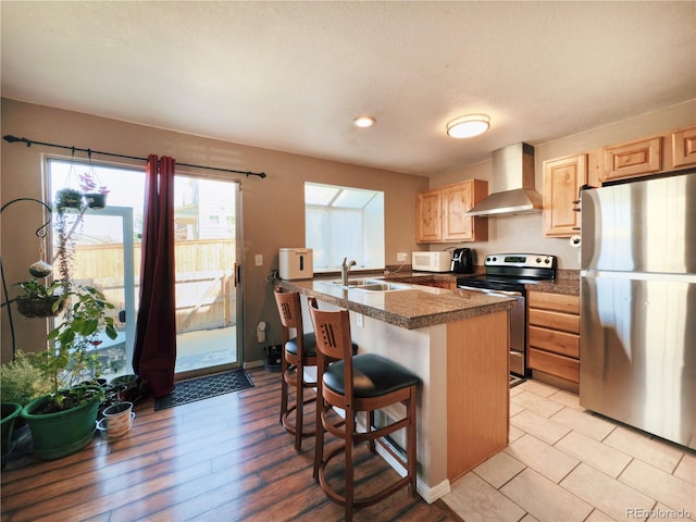 1120 S Waco St Unit A, Aurora, CO 80017 - kitchen featuring stainless steel appliances, wall chimney range hood, light brown cabinets, a breakfast bar area, and tile countertops