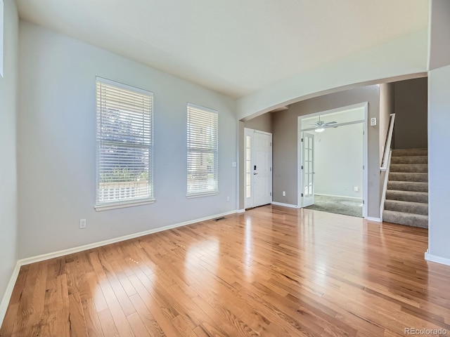 581 N Flat Rock Cir, Aurora, CO 80018 - unfurnished living room featuring stairway, arched walkways, wood finished floors, and ceiling fan