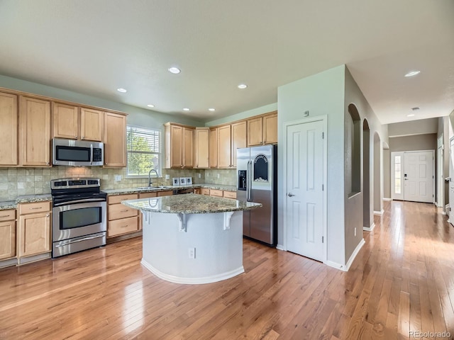 581 N Flat Rock Cir, Aurora, CO 80018 - kitchen featuring appliances with stainless steel finishes, light brown cabinets, decorative backsplash, light stone counters, and light wood finished floors
