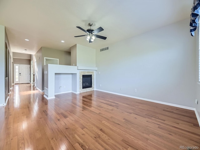 581 N Flat Rock Cir, Aurora, CO 80018 - unfurnished living room with light wood-type flooring, a ceiling fan, a glass covered fireplace, and recessed lighting