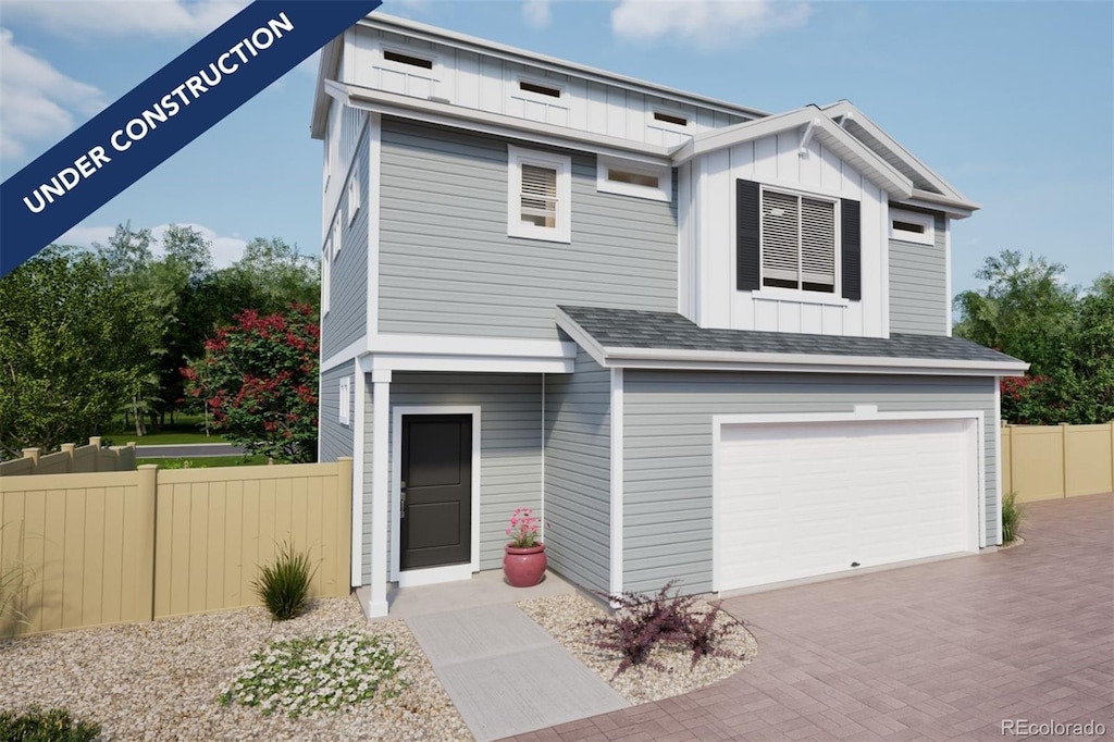 view of front of home with decorative driveway, fence, board and batten siding, and an attached garage