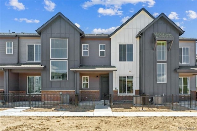 6902 Huddersfield Ln, Castle Pines, CO 80108 - view of front of property with board and batten siding, a fenced front yard, central AC, brick siding, and a gate
