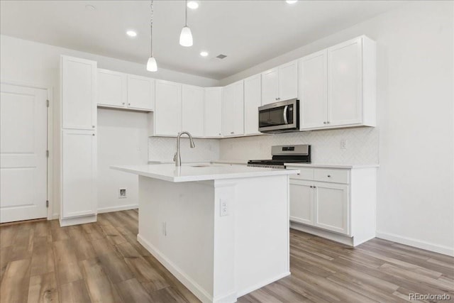 6902 Huddersfield Ln, Castle Pines, CO 80108 - kitchen featuring appliances with stainless steel finishes, white cabinets, tasteful backsplash, light wood finished floors, and recessed lighting