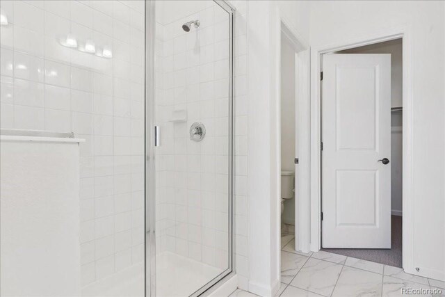 6902 Huddersfield Ln, Castle Pines, CO 80108 - bathroom with a stall shower, toilet, marble finish floors, and baseboards