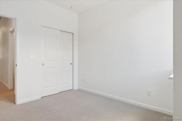 6902 Huddersfield Ln, Castle Pines, CO 80108 - unfurnished bedroom with light carpet, baseboards, and a closet