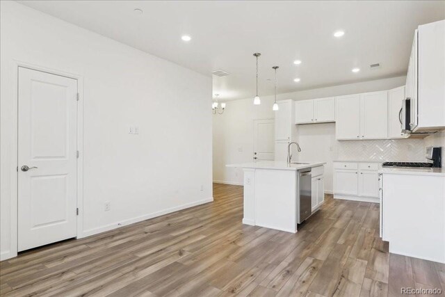 6902 Huddersfield Ln, Castle Pines, CO 80108 - kitchen featuring a sink, light wood-type flooring, stainless steel appliances, decorative backsplash, and white cabinets