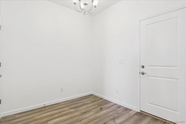 6902 Huddersfield Ln, Castle Pines, CO 80108 - unfurnished room with light wood-style floors, a chandelier, and baseboards