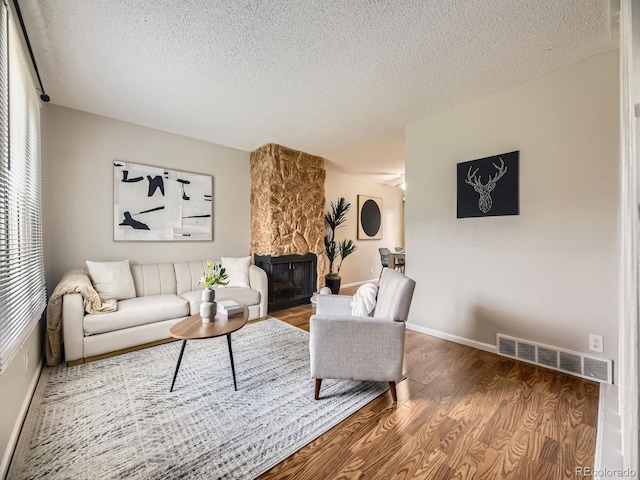 1932 S Oswego Way, Aurora, CO 80014 - living area with a textured ceiling, wood finished floors, a stone fireplace, and baseboards
