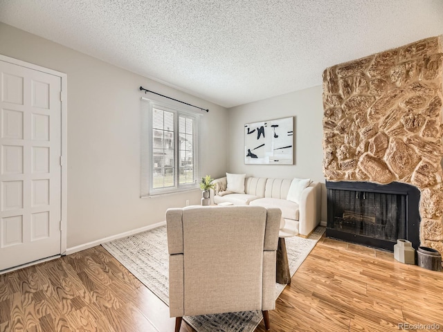1932 S Oswego Way, Aurora, CO 80014 - living room with wood finished floors, a stone fireplace, a textured ceiling, and baseboards