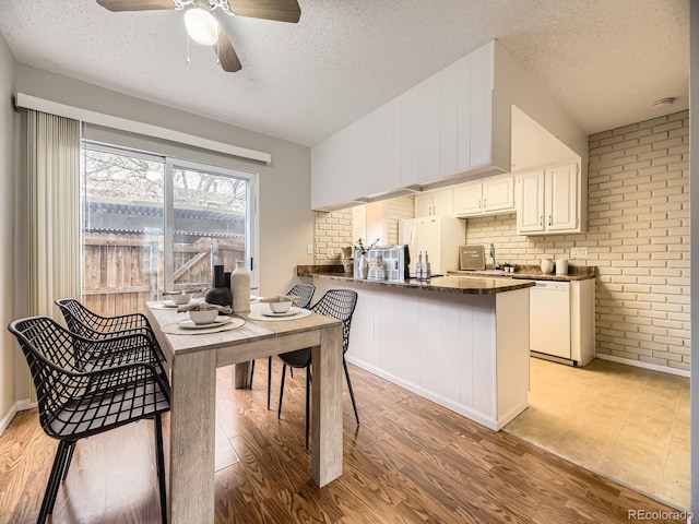 1932 S Oswego Way, Aurora, CO 80014 - kitchen with dark countertops, white appliances, a textured ceiling, a peninsula, and ceiling fan