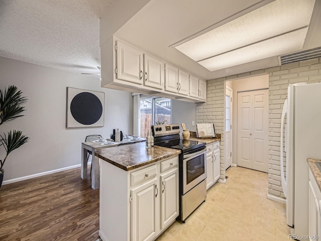 1932 S Oswego Way, Aurora, CO 80014 - kitchen with stainless steel electric stove, freestanding refrigerator, white cabinetry, baseboards, and a textured ceiling