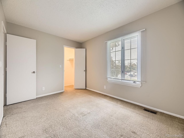 1932 S Oswego Way, Aurora, CO 80014 - unfurnished bedroom featuring carpet, a textured ceiling, baseboards, and a spacious closet