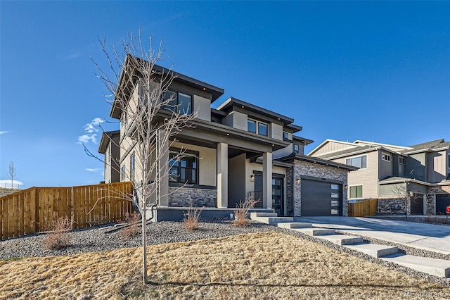 view of front of property with fence, concrete driveway, stucco siding, a garage, and stone siding