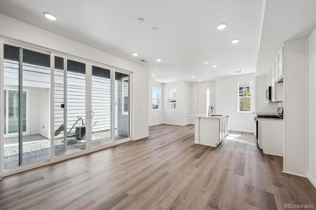 1368 Penner Dr, Erie, CO 80026 - unfurnished living room with healthy amount of natural light, light wood-style floors, baseboards, recessed lighting, and a sink