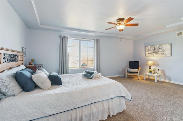 bedroom featuring a tray ceiling, carpet floors, and baseboards