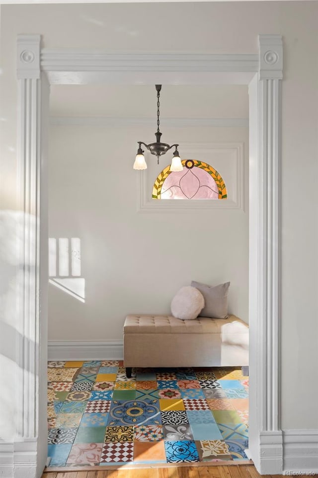 sitting room with crown molding, wood-type flooring, and a chandelier