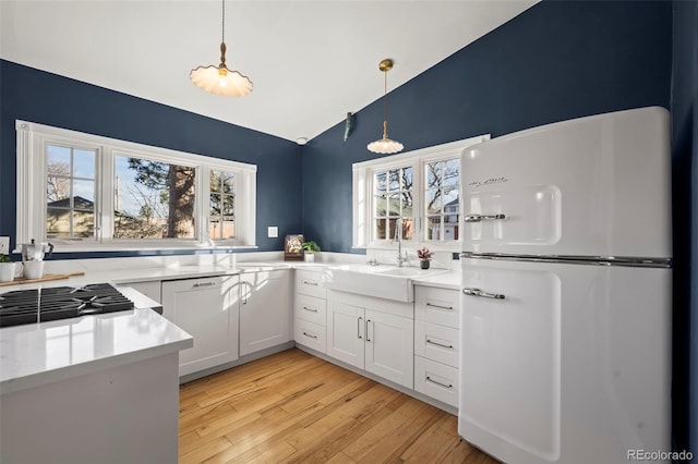 kitchen featuring sink, white cabinetry, fridge, pendant lighting, and a healthy amount of sunlight