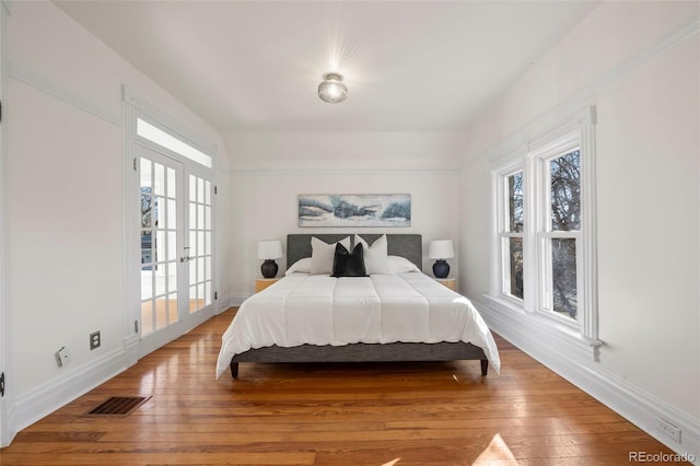 bedroom with hardwood / wood-style flooring and french doors