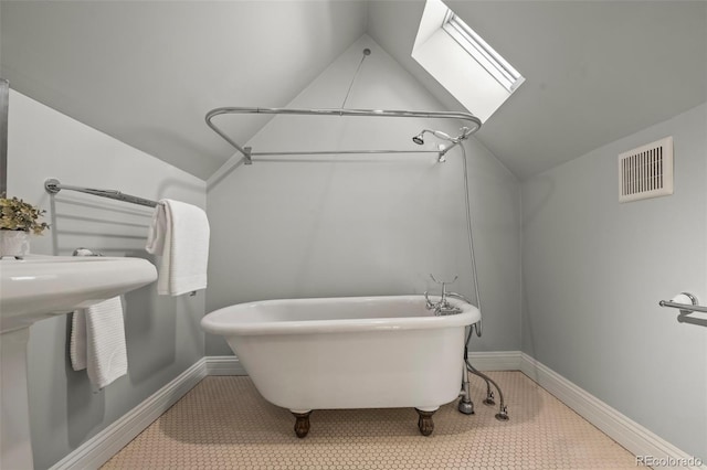 bathroom featuring tile patterned floors, vaulted ceiling with skylight, and a tub