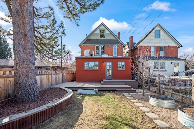 rear view of house featuring a wooden deck and a yard