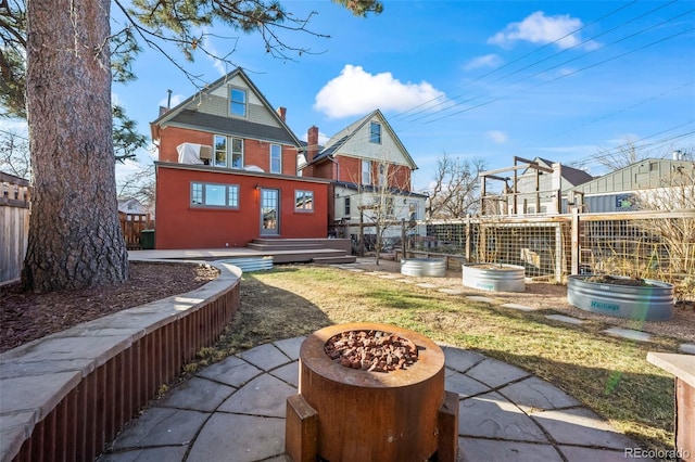 rear view of house featuring a patio, an outbuilding, and an outdoor fire pit