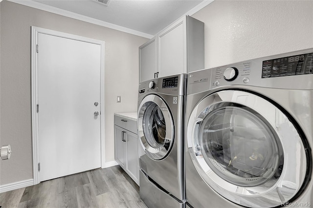 clothes washing area featuring cabinets, crown molding, independent washer and dryer, and light wood-type flooring