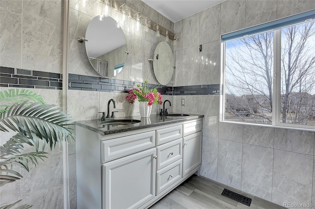 bathroom with vanity, hardwood / wood-style floors, and tile walls