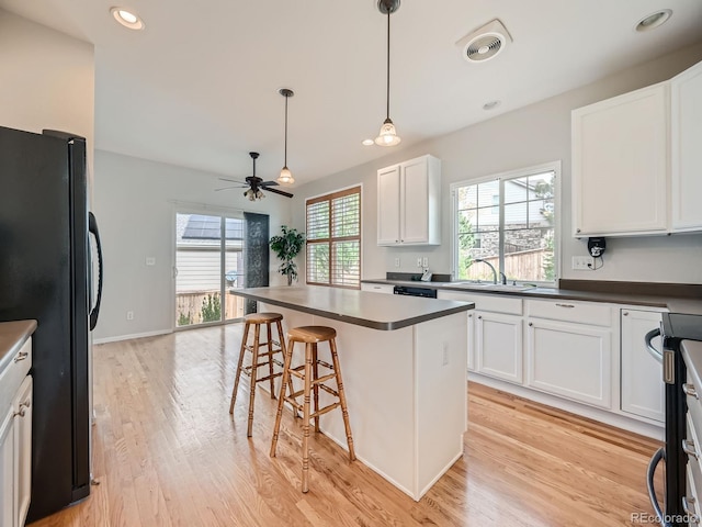 kitchen featuring a healthy amount of sunlight, a center island, a kitchen breakfast bar, and black refrigerator